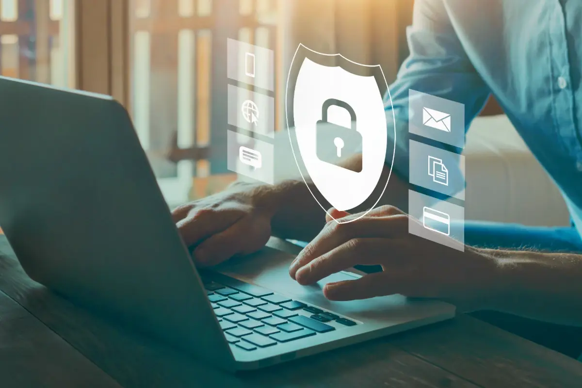 Person using a laptop with overlay icons of a security shield and padlock representing data protection.