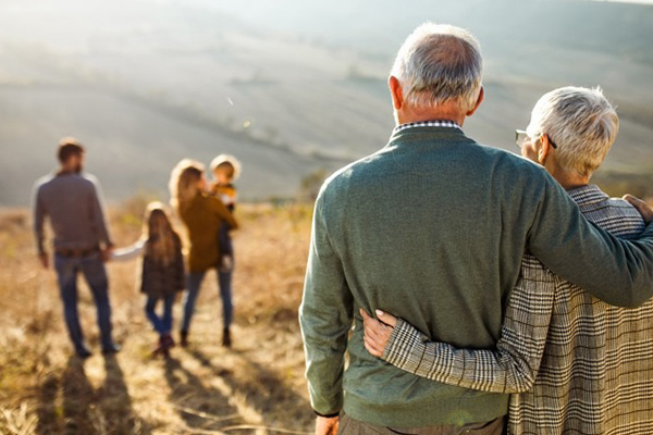 An image of a middle aged couple in a field watching their family from a distance